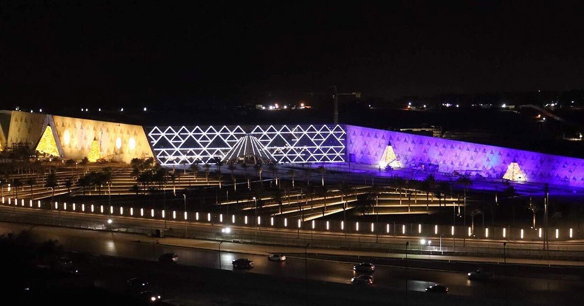 The Grand Egyptian Museum at night with purple, white and yellow LED lighting